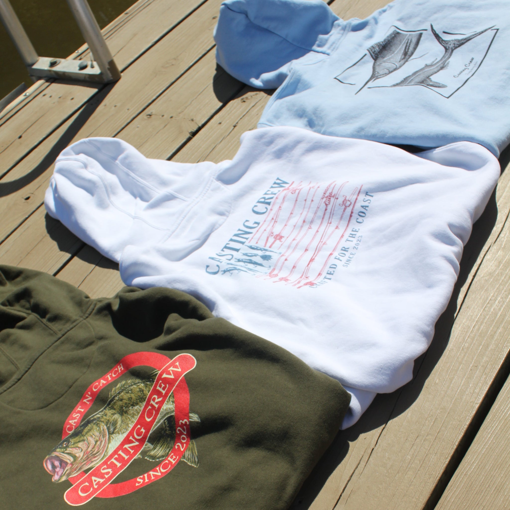 Two t-shirts with 'Casting Crew' logo on a wooden surface